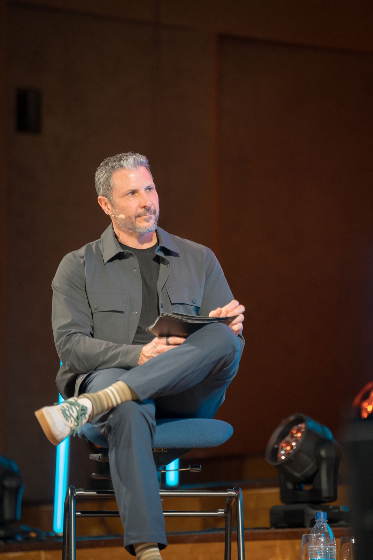 Eric Malzone seated cross-legged on stage holding interview notes